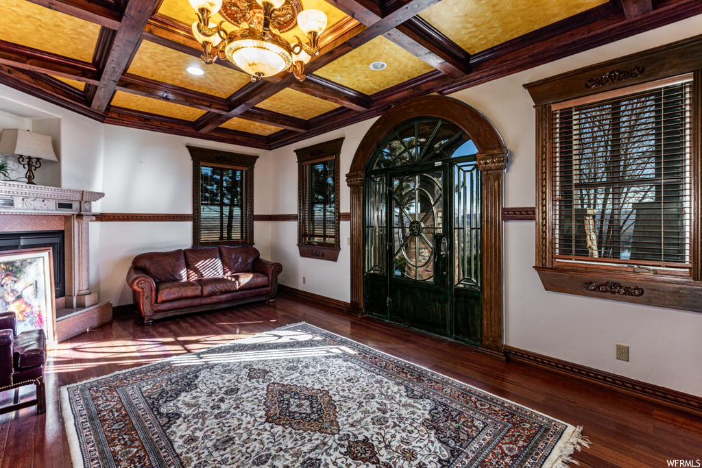 Foyer with coffered ceiling, dark wood-type flooring, a chandelier, and beamed ceiling