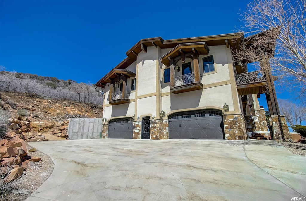 View of side of home featuring a balcony and a garage
