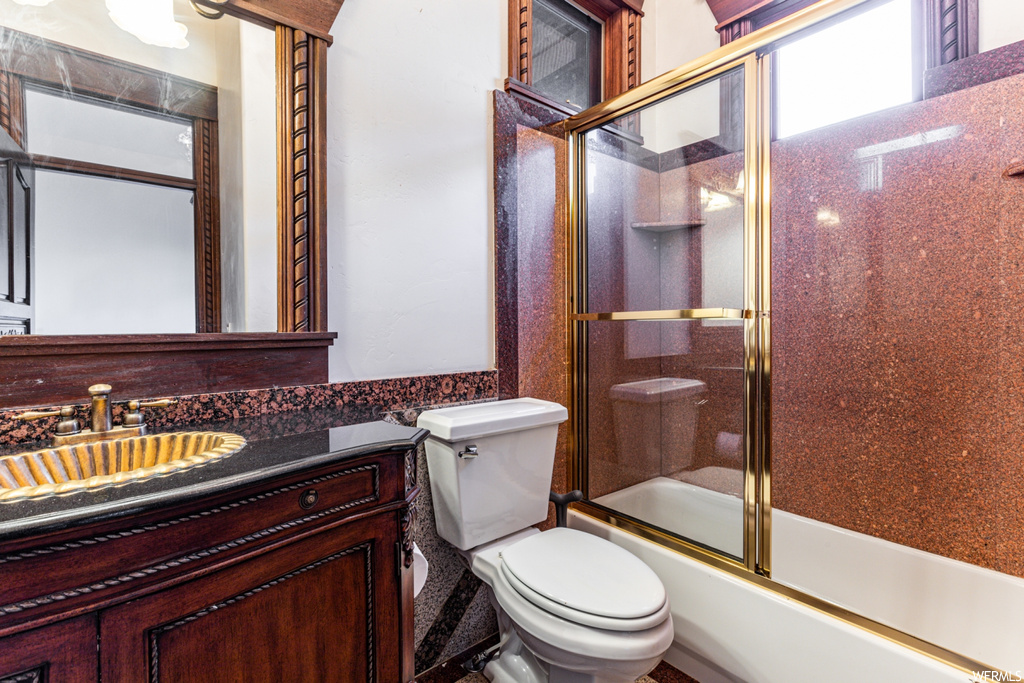 Full bathroom featuring toilet, enclosed tub / shower combo, and vanity