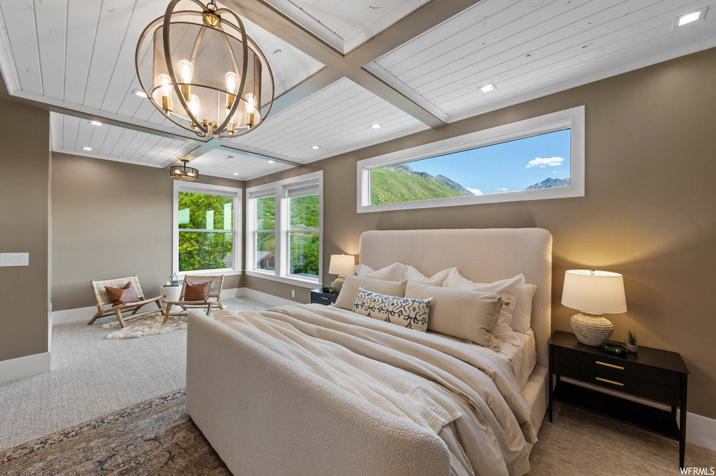 Carpeted bedroom featuring beamed ceiling and natural light