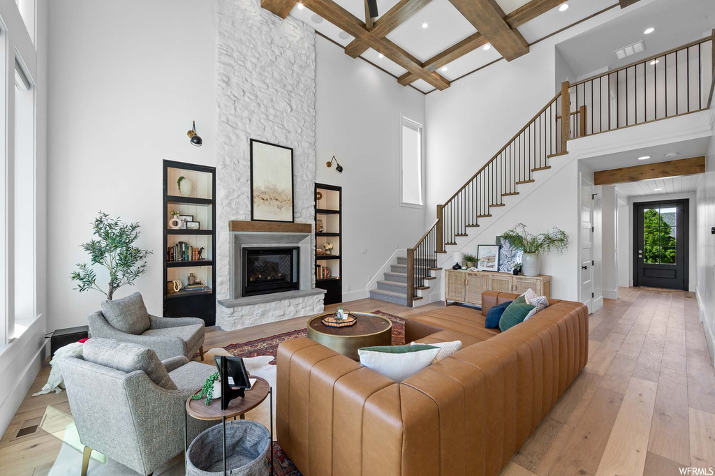 Living room with a fireplace, a high ceiling, wood-type flooring, beamed ceiling, and coffered ceiling