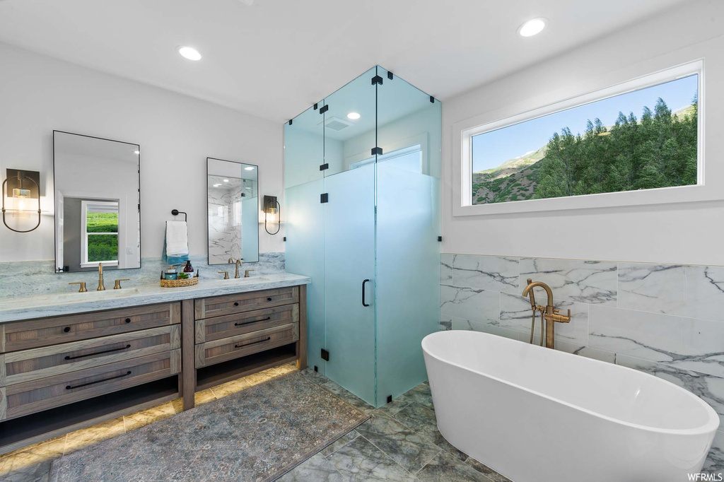 Bathroom featuring natural light, mirror, double sink vanity, and shower with separate bathtub