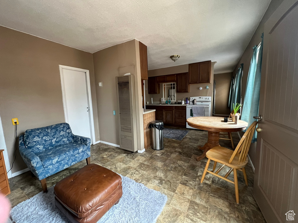 Kitchen featuring electric range oven, light countertops, a heating unit, stone finish floors, and baseboards