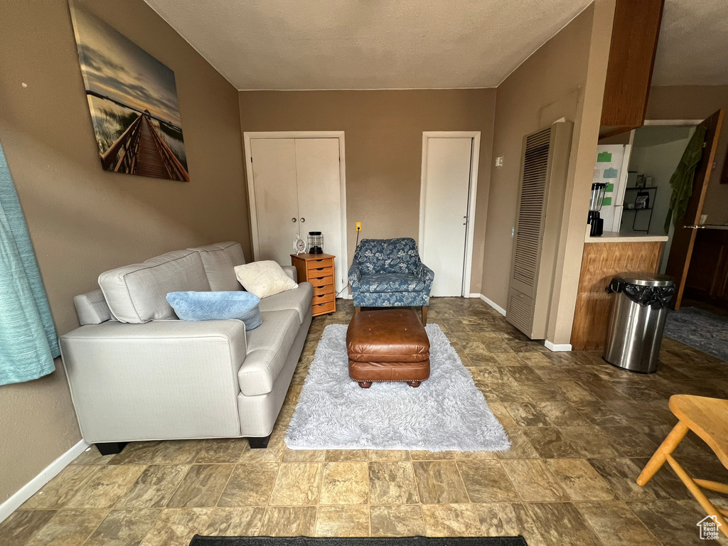 Living area with baseboards, stone finish flooring, and a heating unit