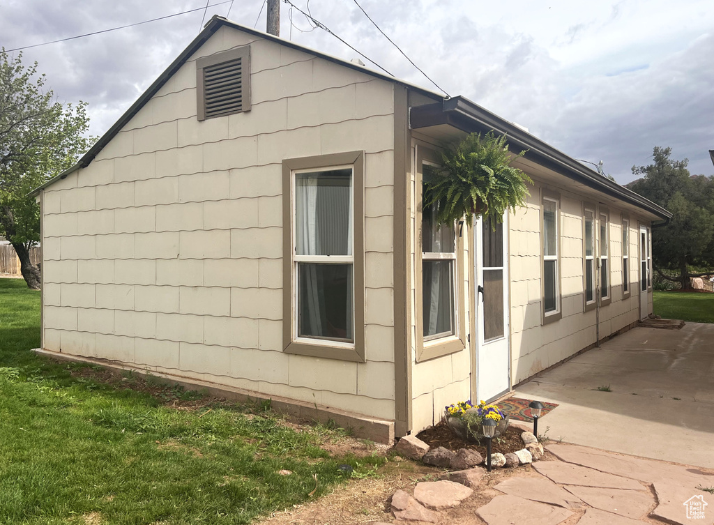 View of side of property with a patio area and a lawn