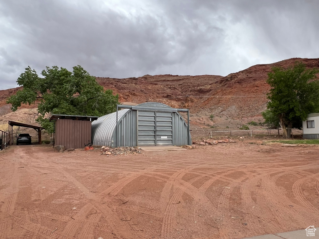 View of shed featuring fence, a mountain view, and a carport