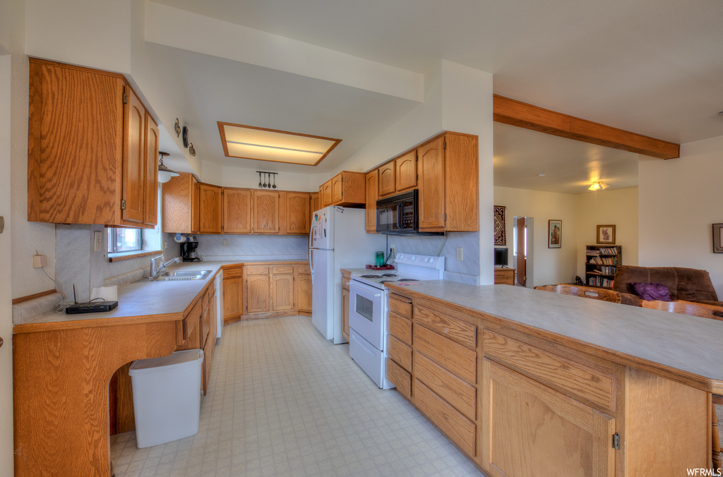 Kitchen featuring microwave, electric range oven, light countertops, brown cabinetry, and light tile floors
