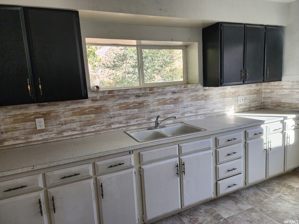 Kitchen featuring plenty of natural light, sink, backsplash, and white cabinets