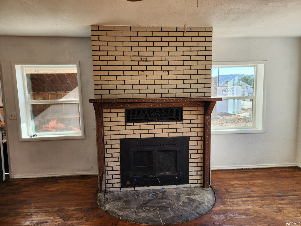 Interior details featuring a brick fireplace and dark wood-type flooring