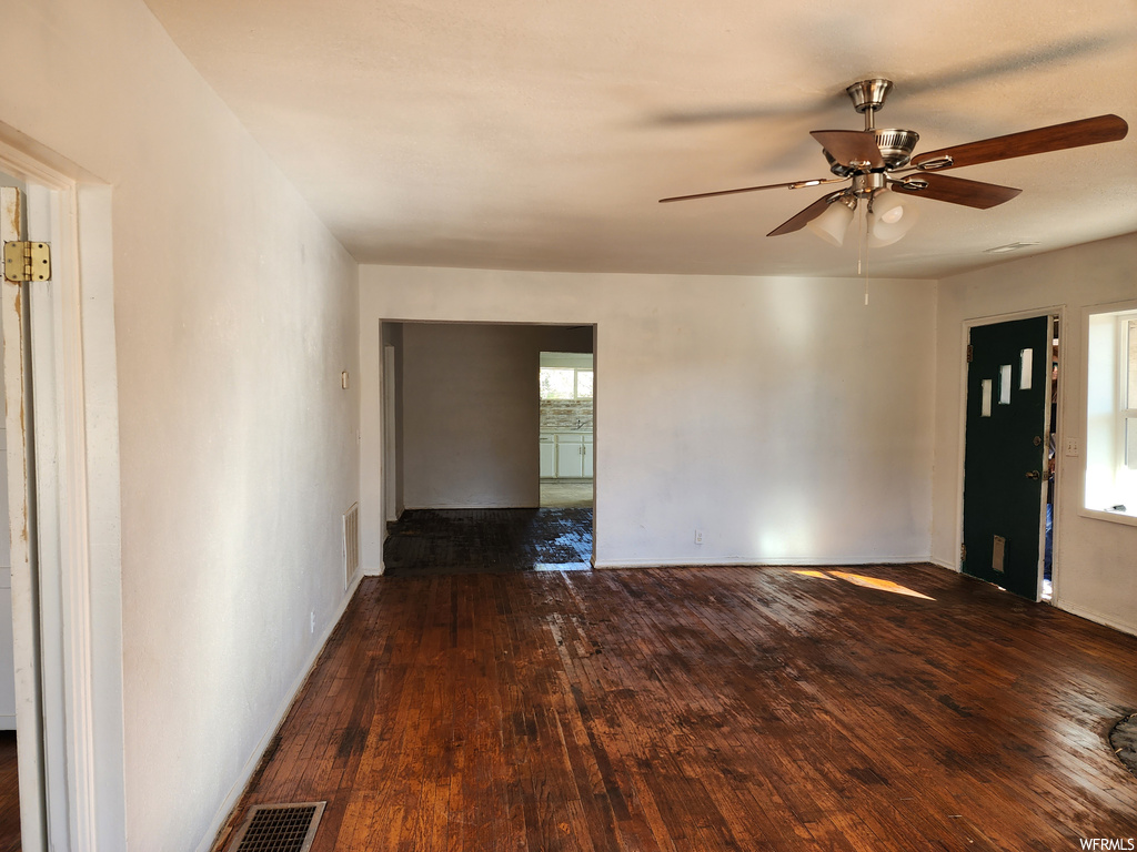 Spare room featuring a wealth of natural light, ceiling fan, and dark wood-type flooring
