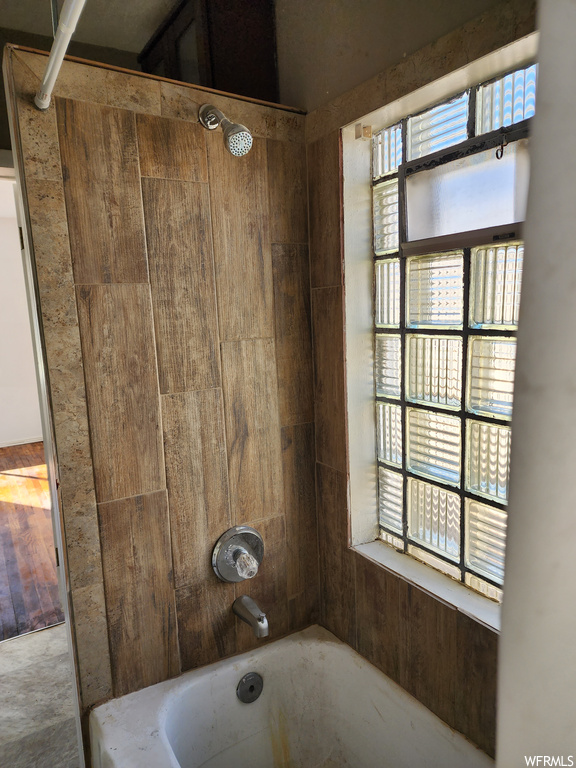 Bathroom with washtub / shower combination and wooden walls