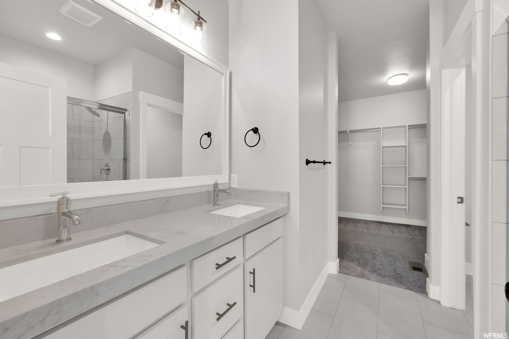 Bathroom featuring tile floors, dual large bowl vanity, a shower, and multiple mirrors