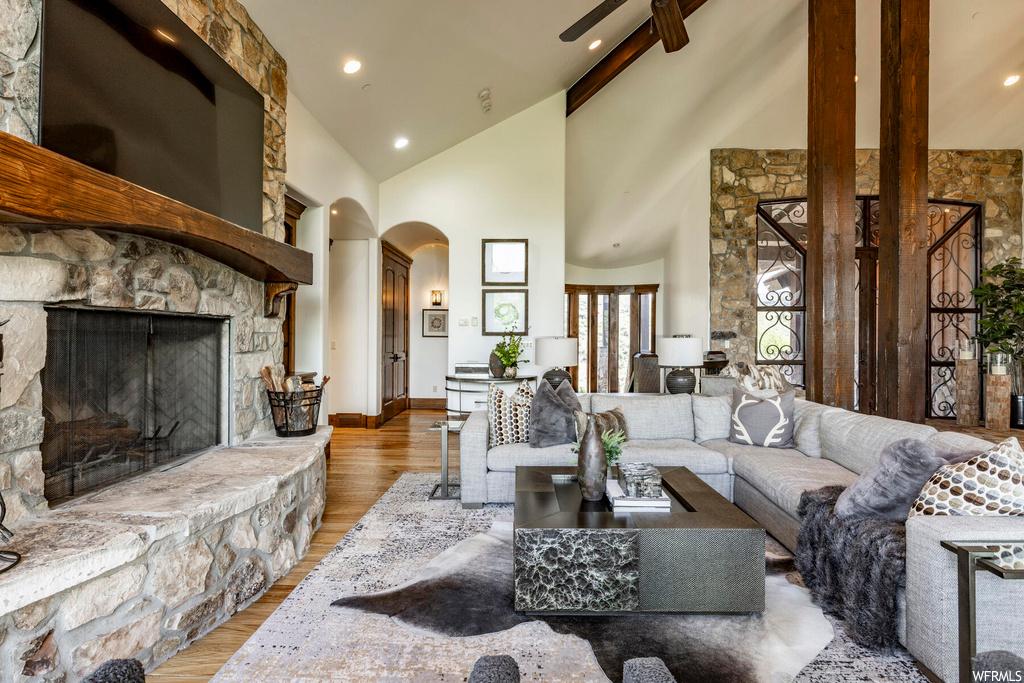 Living room featuring lofted ceiling, a fireplace, hardwood floors, and a high ceiling