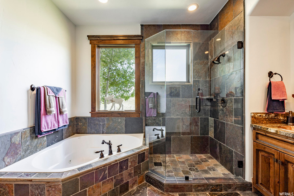 Bathroom with a wealth of natural light, separate shower and tub enclosures, and vanity
