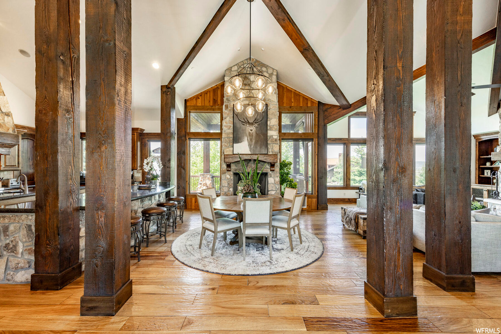 Hardwood floored dining space with lofted ceiling with beams, a fireplace, and natural light