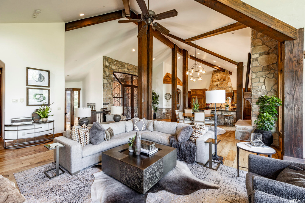 Hardwood floored living room with a ceiling fan and vaulted ceiling with beams