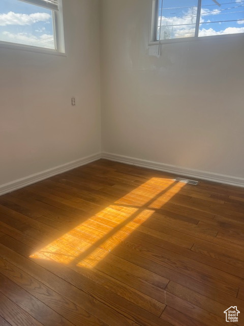 Spare room featuring a healthy amount of sunlight and dark hardwood / wood-style floors