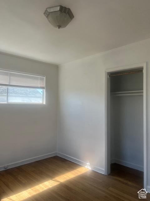Unfurnished bedroom featuring dark hardwood / wood-style flooring and a closet