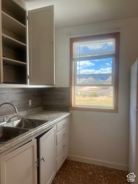 Kitchen with backsplash, sink, white cabinetry, and white fridge