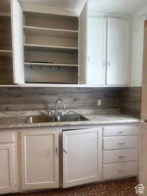 Kitchen featuring white cabinets, sink, and tasteful backsplash