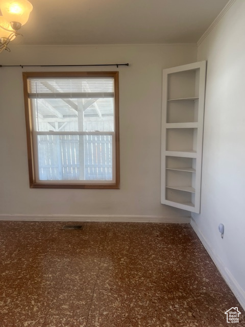 Tiled empty room featuring crown molding and plenty of natural light