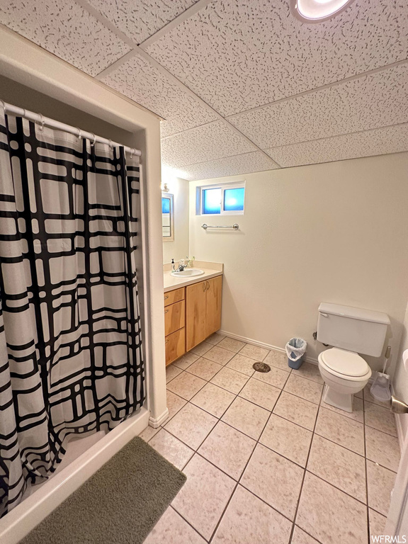 Bathroom with tile floors, vanity, shower curtain, mirror, and toilet