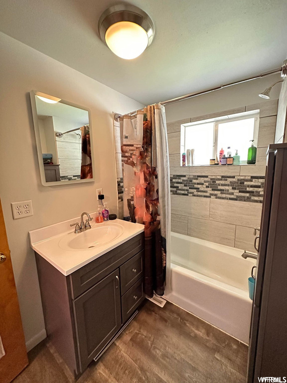 Bathroom with natural light, mirror, oversized vanity, shower / bathtub combination, and shower curtain
