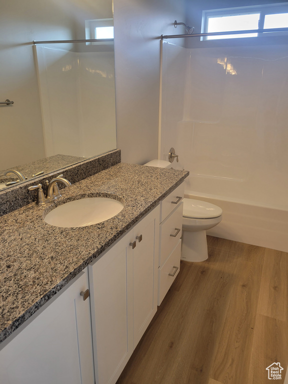 Full bathroom with vanity, hardwood / wood-style flooring, tub / shower combination, and toilet
