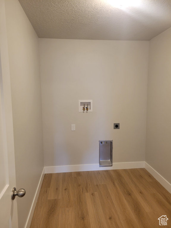Washroom with light hardwood / wood-style floors, hookup for an electric dryer, a textured ceiling, and washer hookup