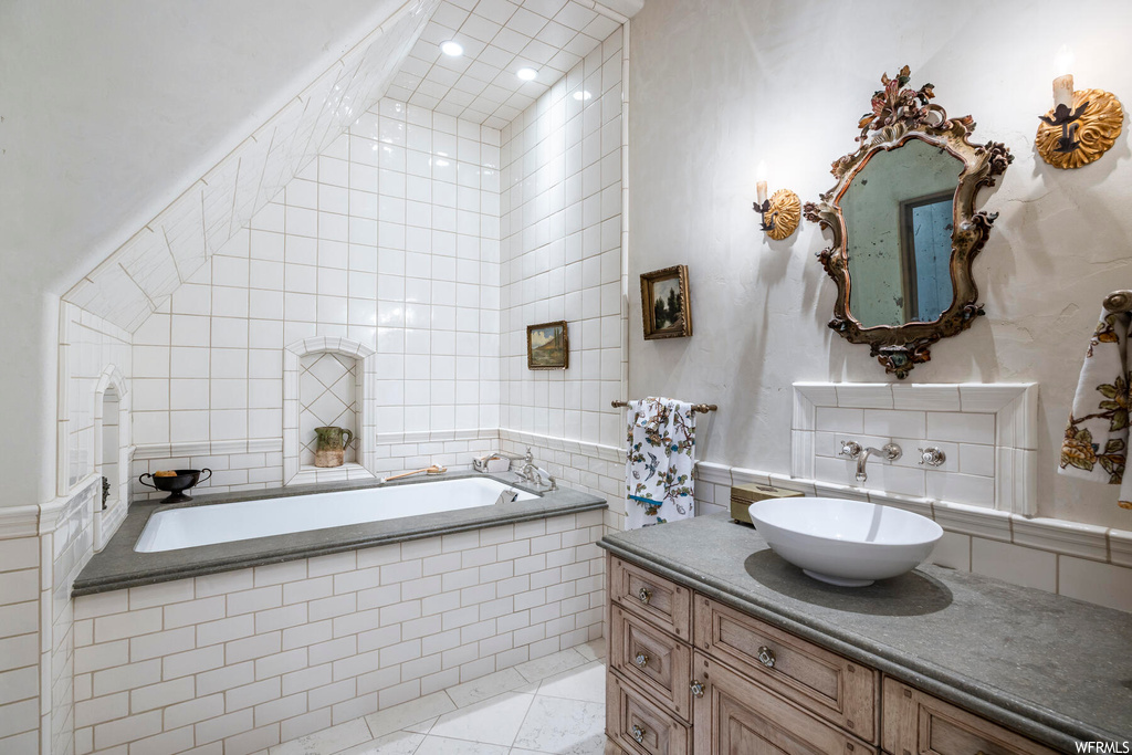 Bathroom with tile floors, vanity, a bathtub, and mirror