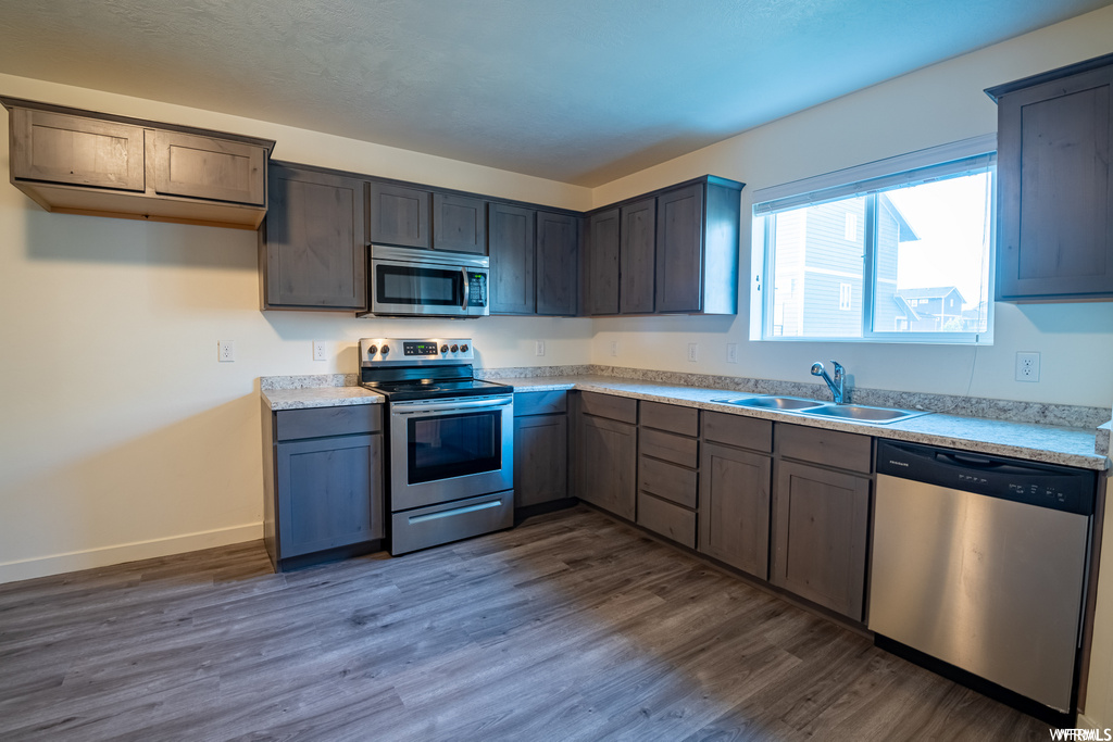 Kitchen featuring natural light, microwave, electric range oven, stainless steel dishwasher, light parquet floors, and light countertops