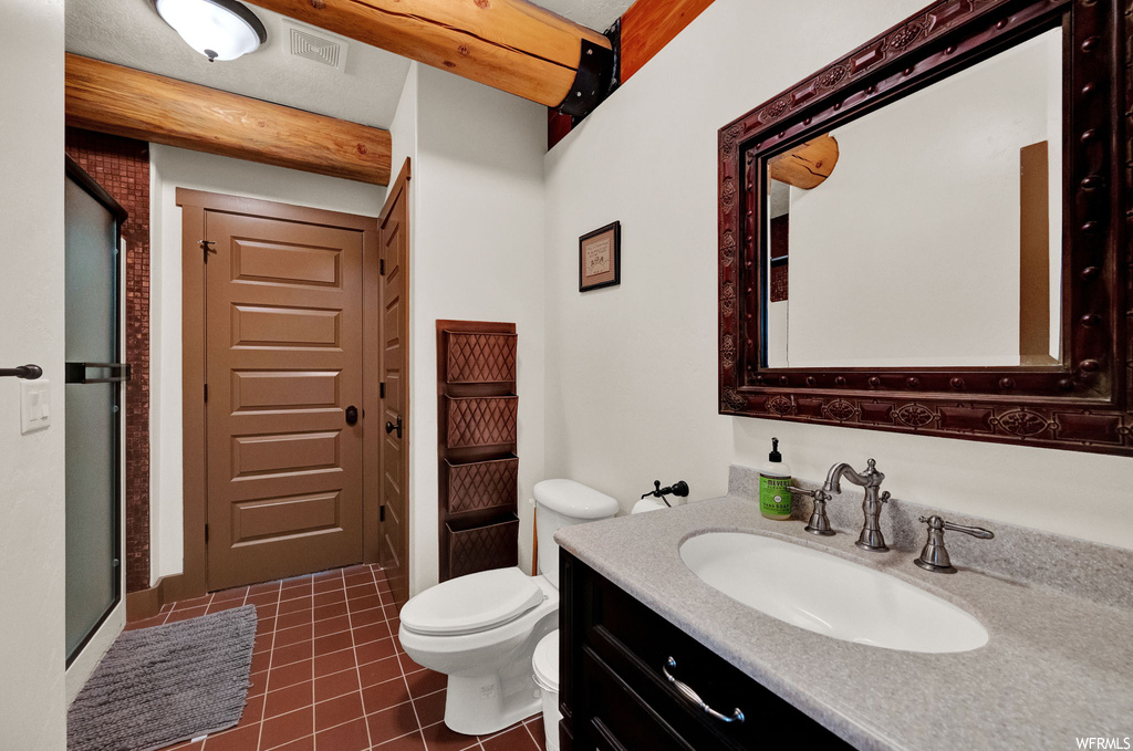 Half bath with tile floors, mirror, toilet, and vanity