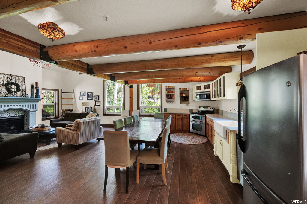 Dining area with a fireplace, hardwood floors, wood beam ceiling, natural light, and microwave