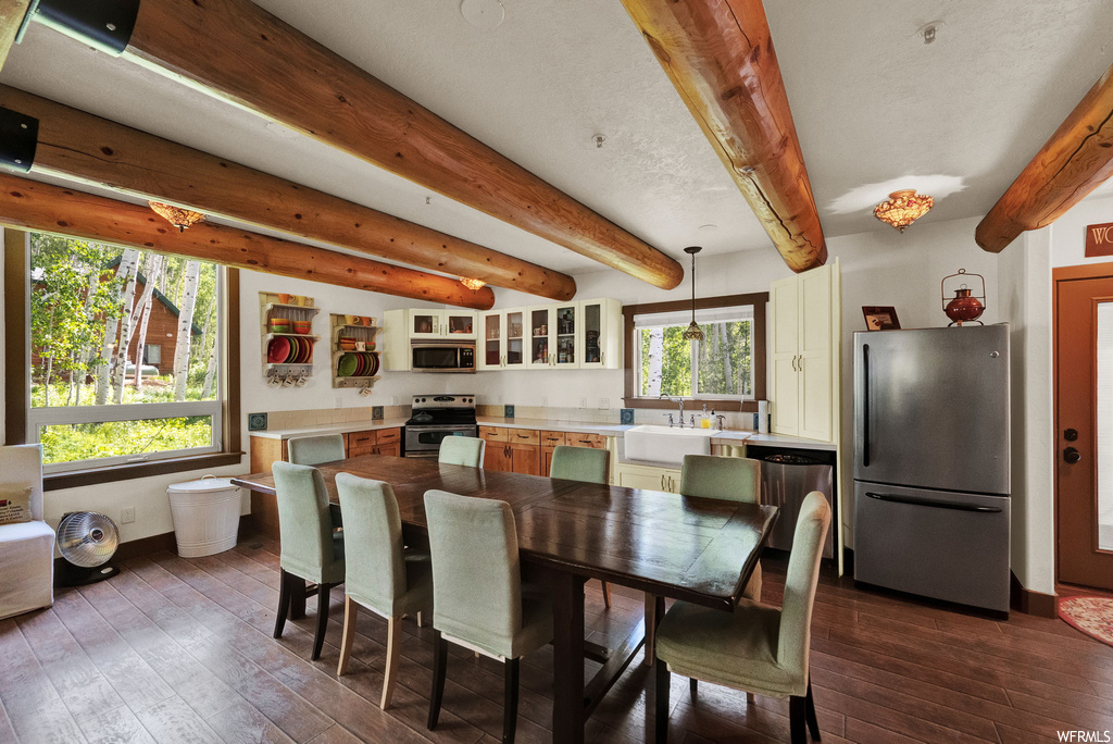 Dining area featuring beamed ceiling, hardwood floors, natural light, and microwave