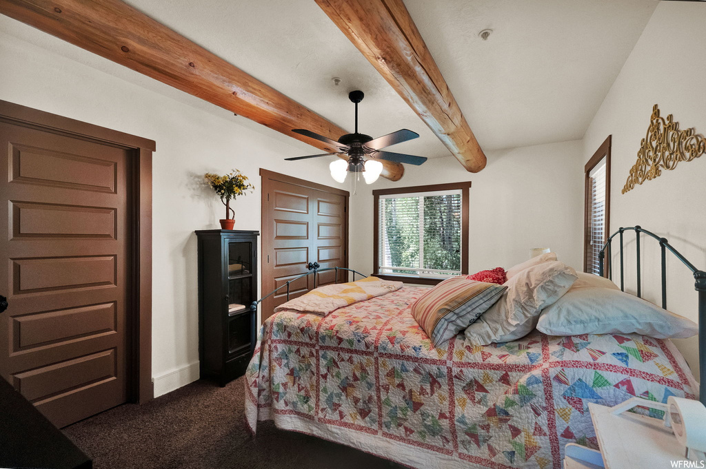 Bedroom featuring carpet, a ceiling fan, wood beam ceiling, and natural light