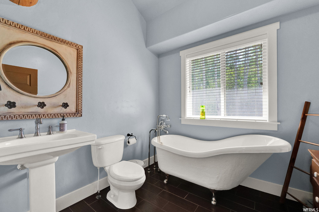 Bathroom with natural light, mirror, toilet, washbasin, and a washtub