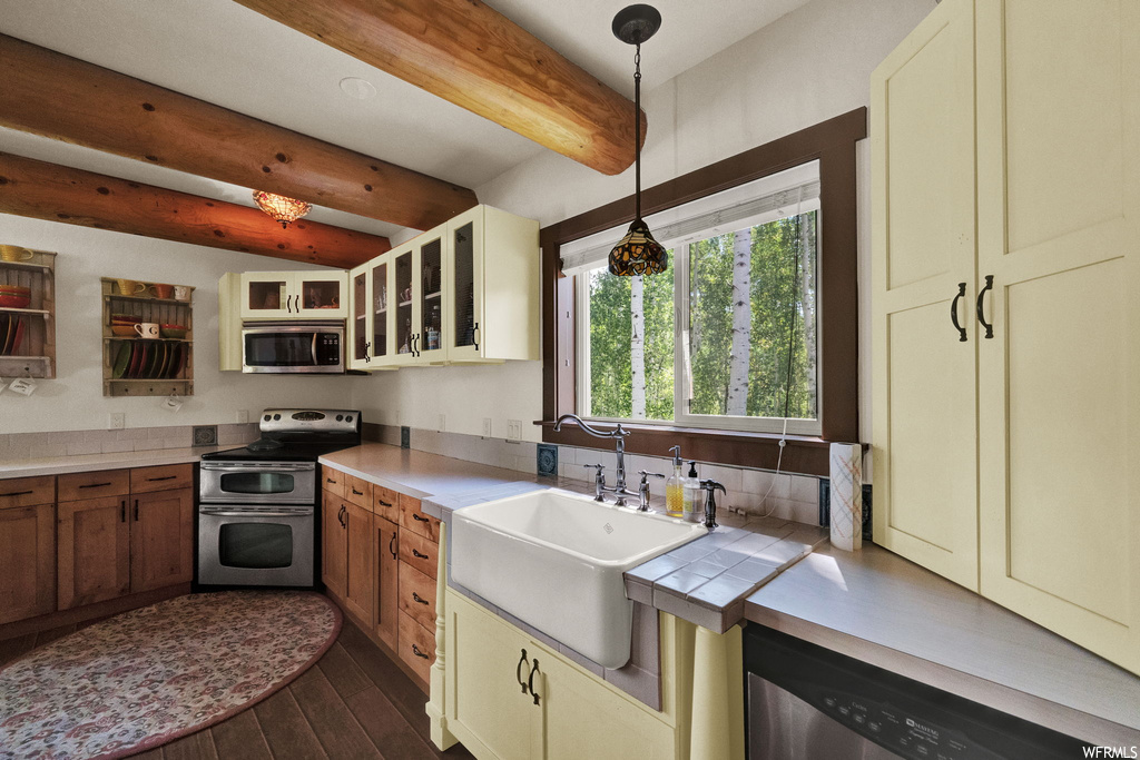 Kitchen with hardwood flooring, natural light, range oven, dishwasher, microwave, pendant lighting, and light countertops