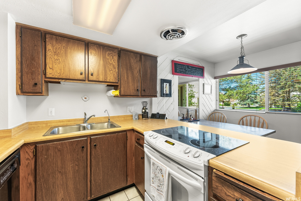 Kitchen featuring tile floors, dishwasher, electric range oven, light countertops, and pendant lighting