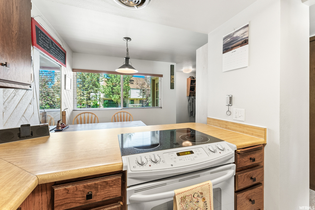 Kitchen featuring a wealth of natural light, electric range oven, light countertops, and pendant lighting