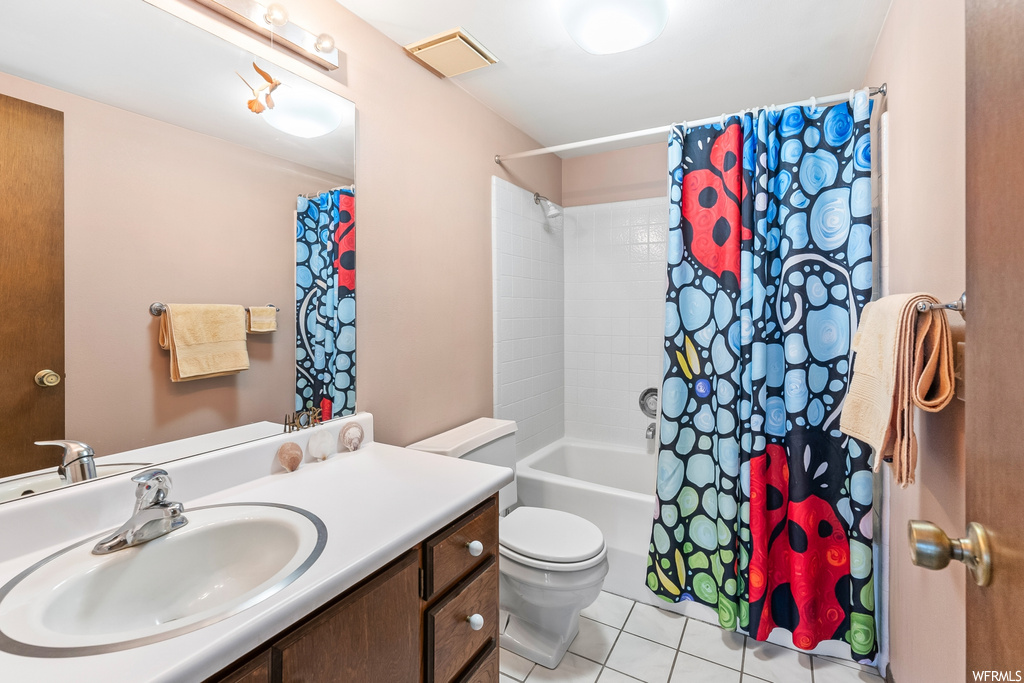 Full bathroom featuring tile flooring, shower curtain, large vanity, mirror, shower / bathing tub combination, and toilet