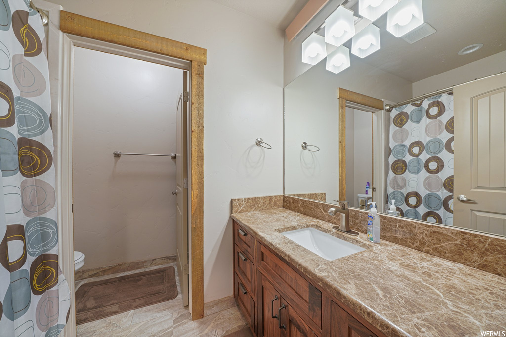 Bathroom featuring tile flooring, mirror, vanity, shower curtain, and toilet
