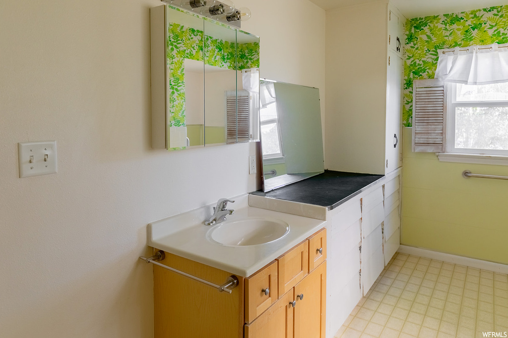 Bathroom featuring tile floors, natural light, mirror, and vanity