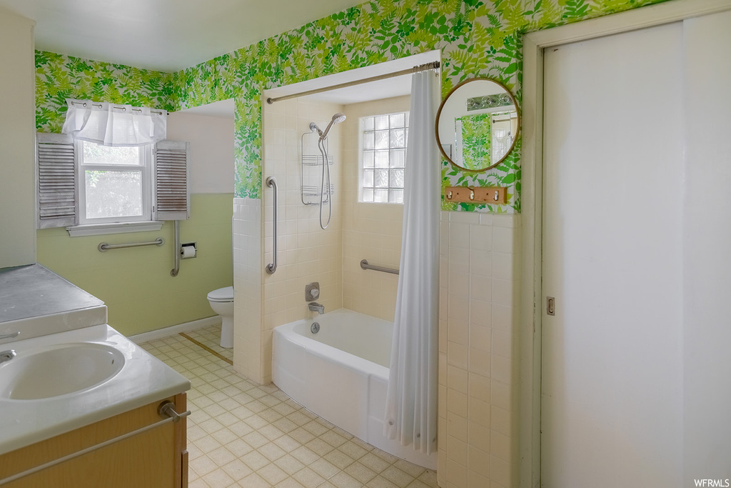 Full bathroom featuring natural light, tile flooring, toilet, vanity, shower / bath combination, shower curtain, and dual mirrors