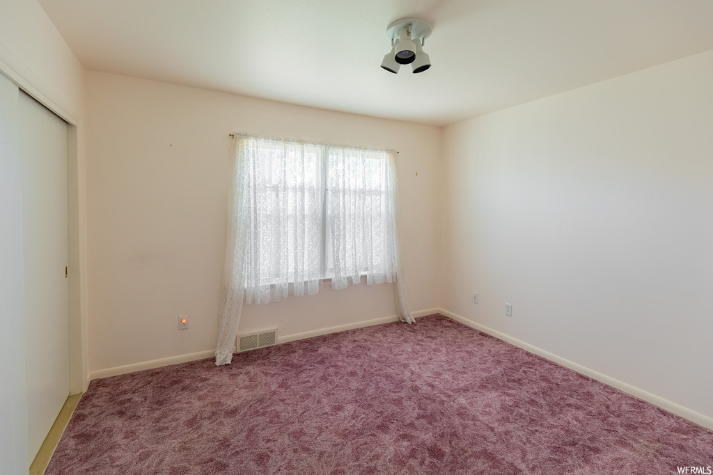 Carpeted empty room featuring natural light