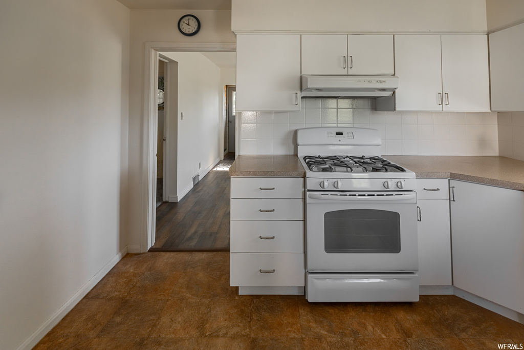 Kitchen featuring exhaust hood, gas range oven, light countertops, dark hardwood floors, and white cabinets