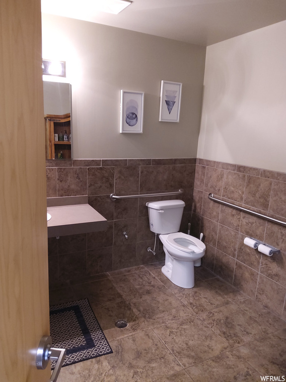 Bathroom featuring skylight, tile flooring, mirror, and toilet