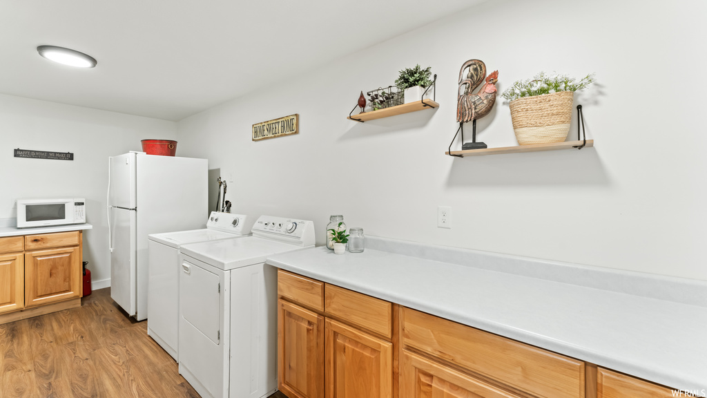 Clothes washing area with wood-type flooring, microwave, and separate washer and dryer