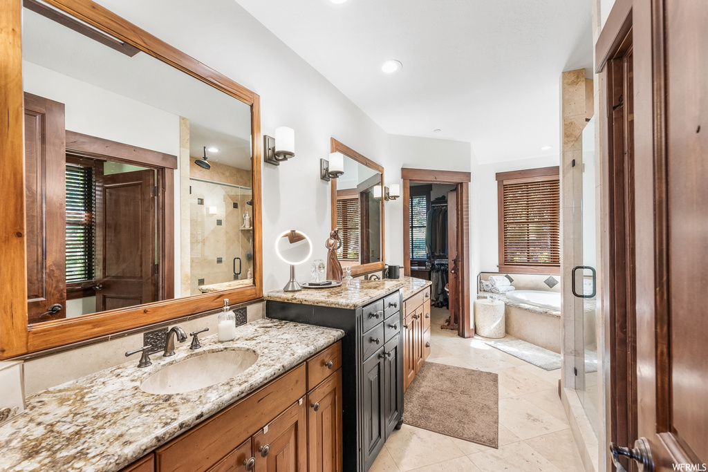 Bathroom featuring tile flooring, mirror, shower with separate bathtub, and his and hers large vanity