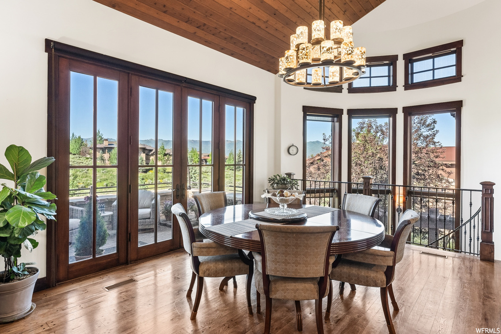 Hardwood floored dining room featuring french doors, a chandelier, and natural light