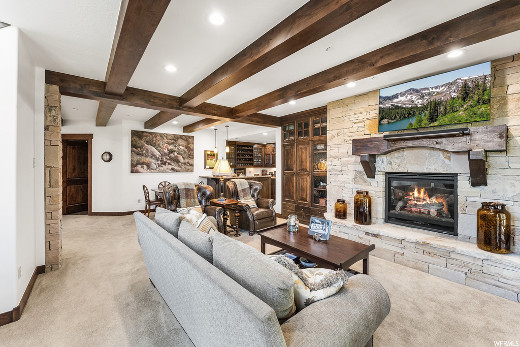 Carpeted living room featuring wood beam ceiling, a fireplace, and TV